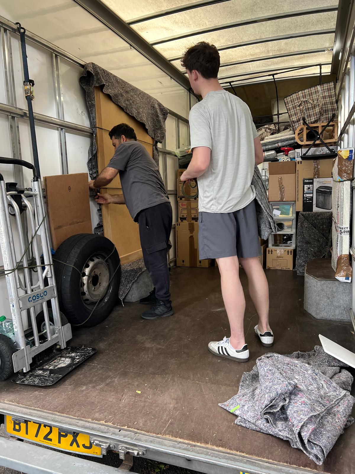 Movers carefully loading wrapped furniture inside the removals van